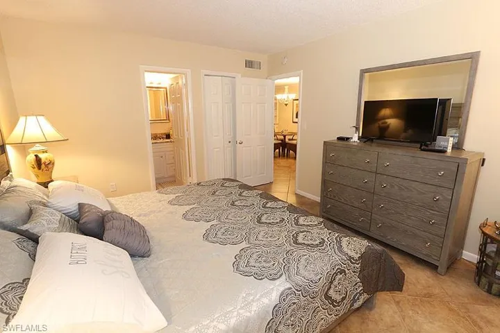 Bedroom featuring a notable chandelier, a closet, ensuite bathroom, and light tile floors
