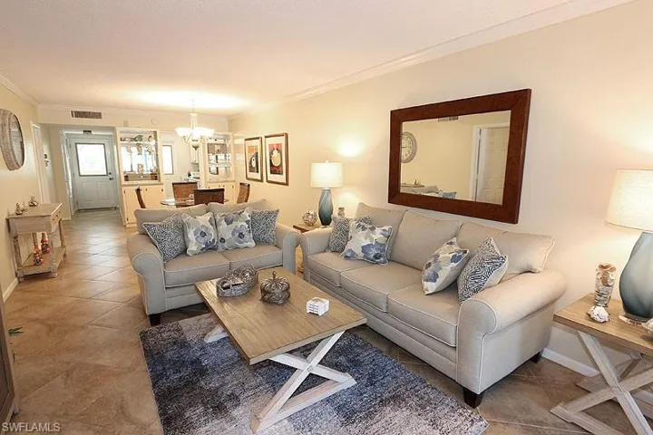 Living room with tile floors, ornamental molding, and an inviting chandelier