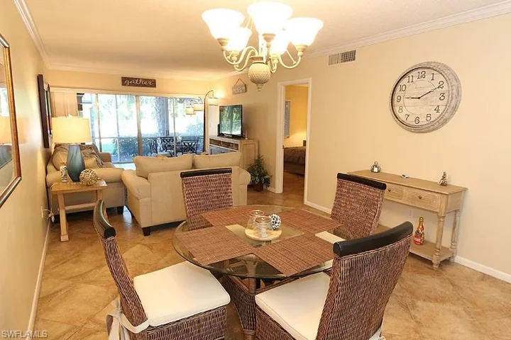 Tiled dining area featuring a chandelier and ornamental molding