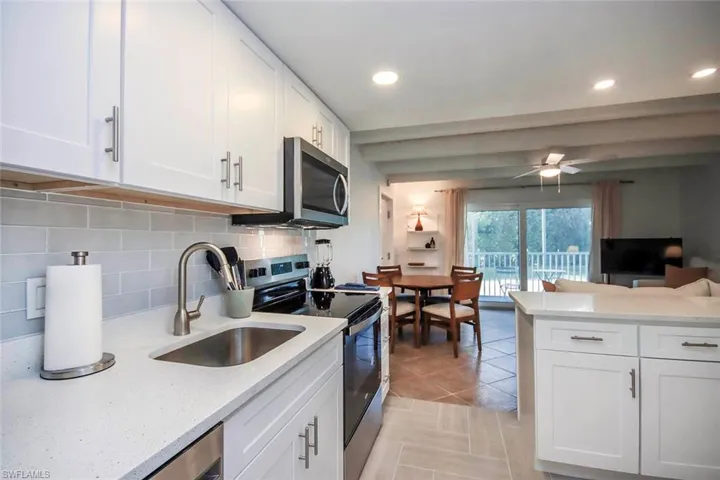 Kitchen with appliances with stainless steel finishes, white cabinetry, light stone counters, decorative backsplash, and recessed lighting