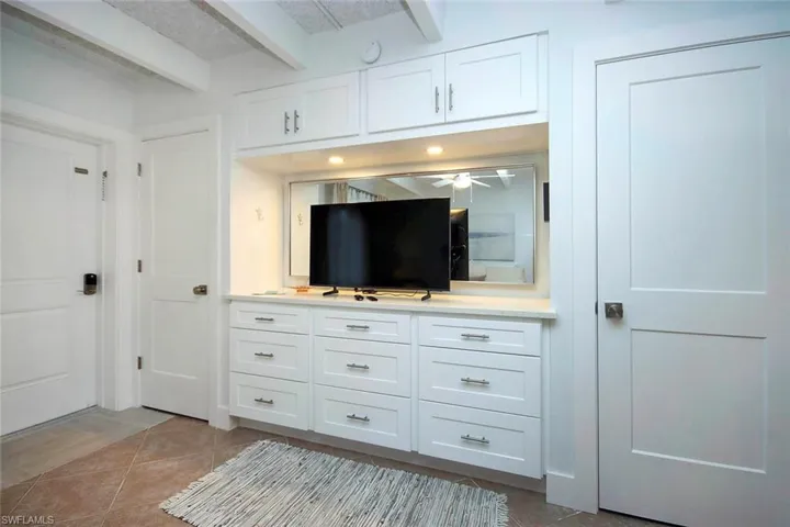 Living area featuring beam ceiling and light tile patterned flooring