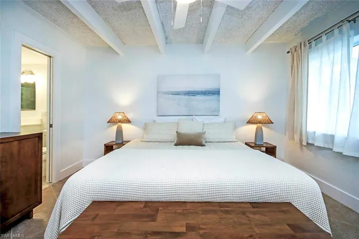 Bedroom with beam ceiling, ceiling fan, and ensuite bath