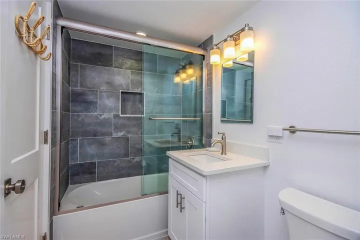 Bathroom with combined bath / shower with glass door and vanity