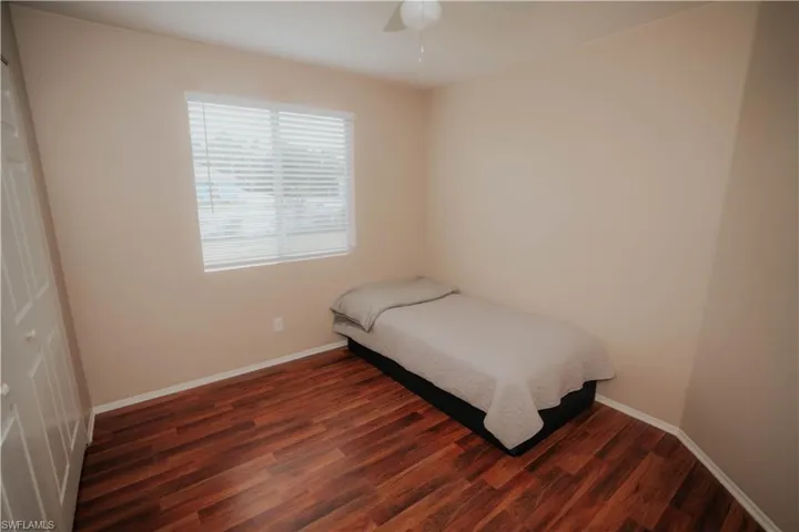 Wood-finish flooring with neutral wall tones and a window featuring horizontal blinds