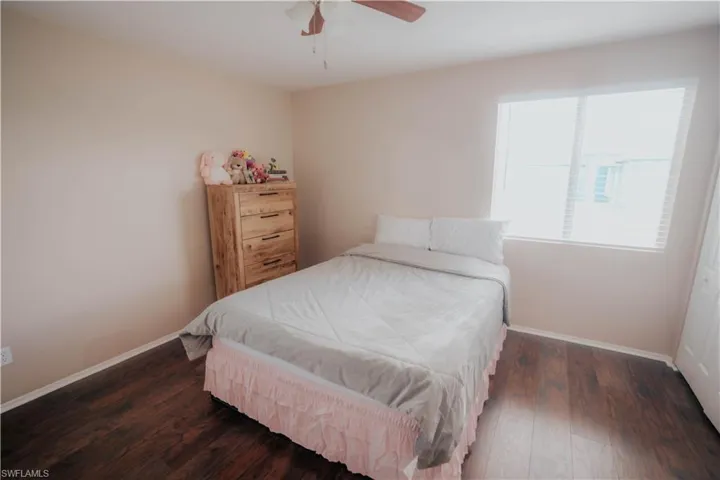 Wood-finish flooring, ceiling fan with integrated lighting, window with blinds, and bi-fold closet doors