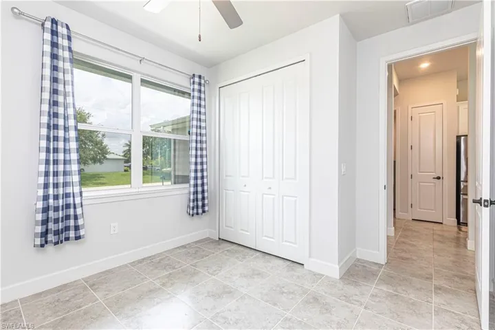 Unfurnished bedroom with a closet, light tile patterned floors, multiple windows, and ceiling fan