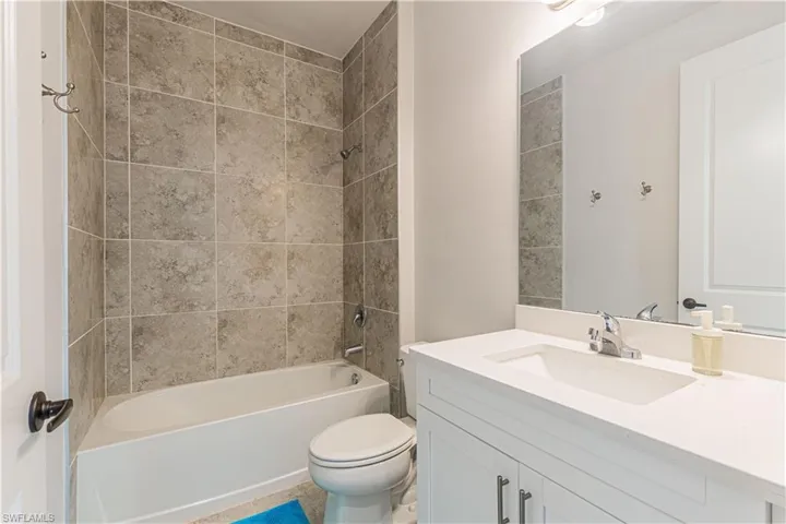 Full bathroom featuring vanity, tiled shower / bath combo, and toilet