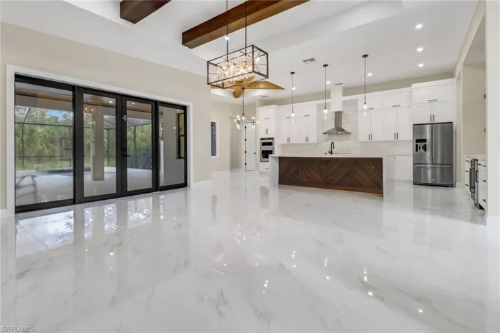 Kitchen with stainless steel fridge, pendant lighting, beam ceiling, a center island, and a chandelier