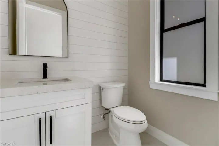 Bathroom with toilet, wooden walls, and vanity