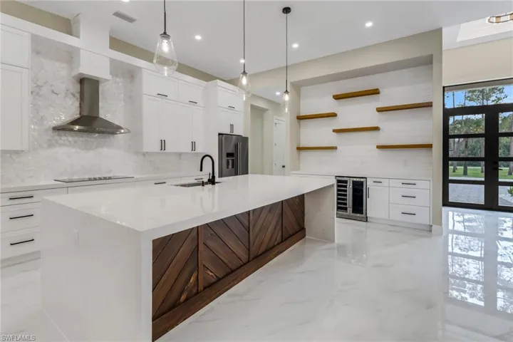 Kitchen with a wealth of natural light, sink, a kitchen island with sink, and stainless steel refrigerator with ice dispenser