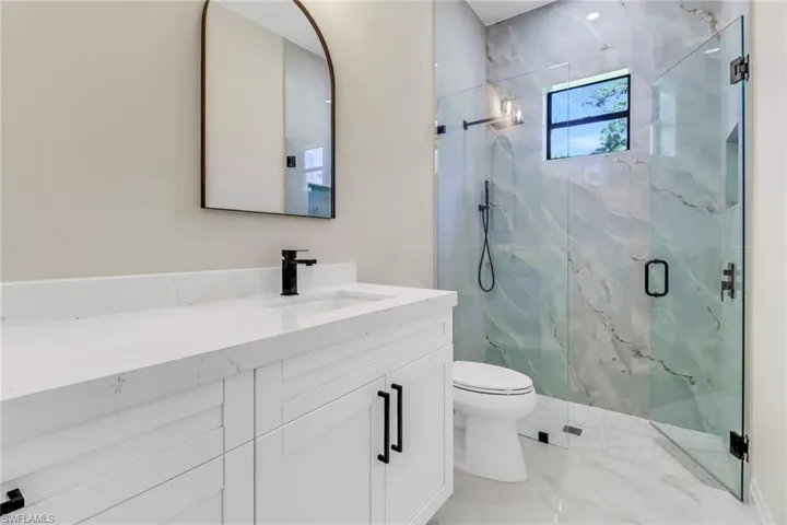 Bathroom featuring vanity, toilet, and an enclosed shower