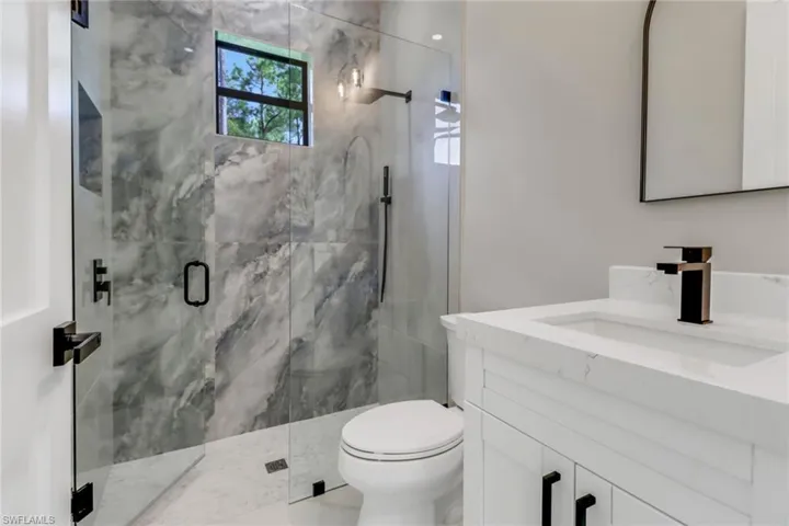 Bathroom featuring vanity, toilet, and a shower with door