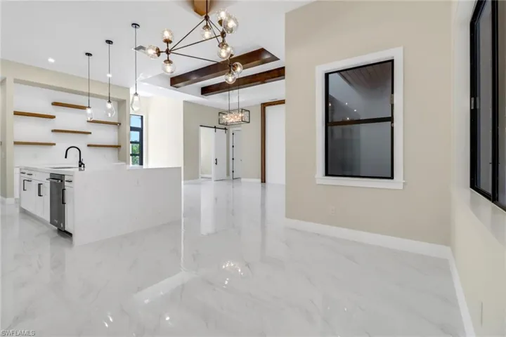 Kitchen featuring a notable chandelier, pendant lighting, white cabinetry, and sink