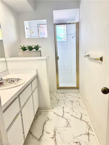 Bathroom with vanity, a shower stall, and light marble finish floors