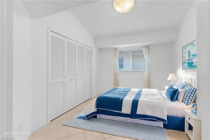 Bedroom featuring vaulted ceiling, a closet, and light tile patterned flooring