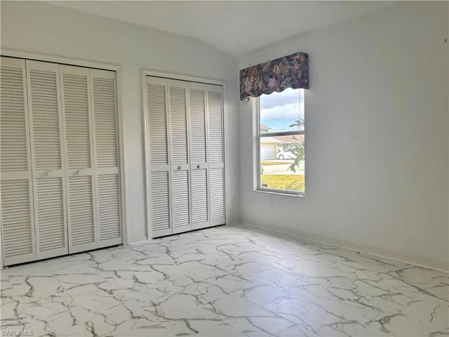 Unfurnished bedroom with two closets and vaulted ceiling