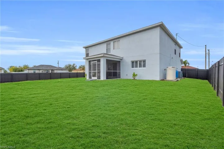 Back of property featuring central AC unit, a yard, and a sunroom