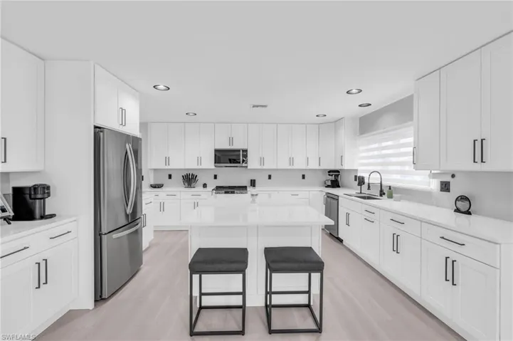 Kitchen with sink, white cabinets, a kitchen breakfast bar, a center island, and stainless steel appliances