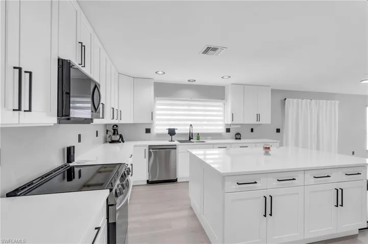 Kitchen featuring sink, white cabinetry, a center island, stainless steel appliances, and light hardwood / wood-style floors