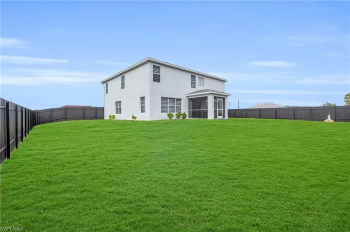 Back of house featuring a sunroom and a lawn