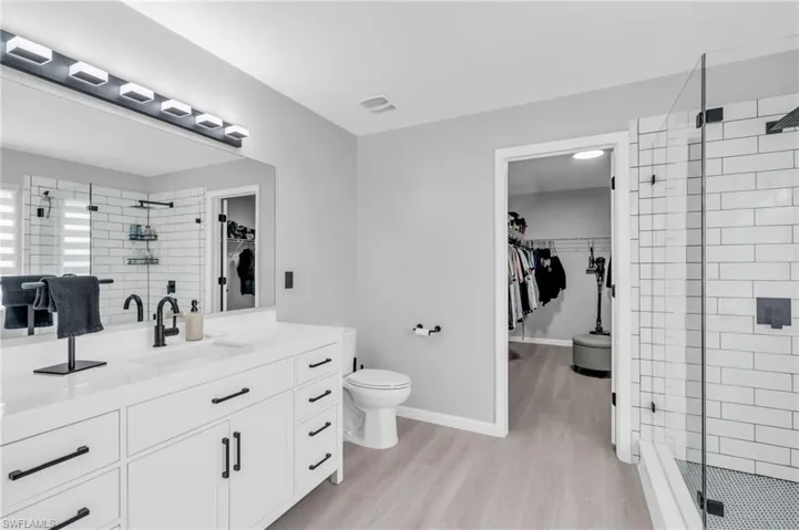 Bathroom featuring vanity, toilet, a shower with shower door, and hardwood / wood-style floors
