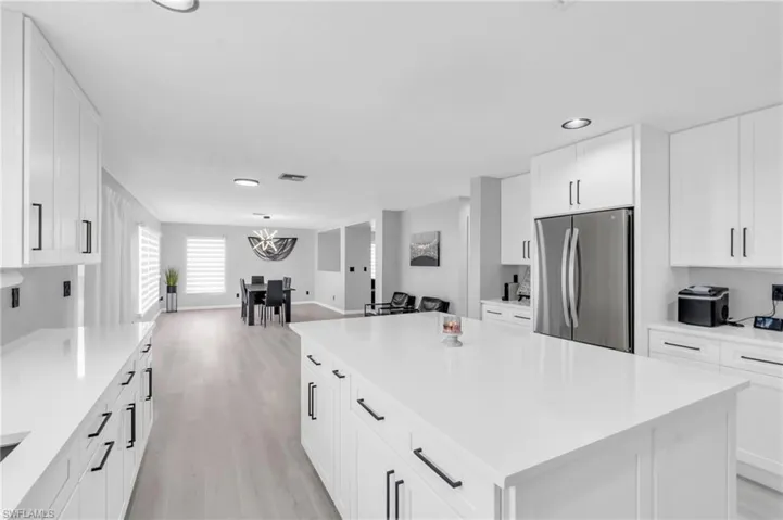 Kitchen with white cabinets, a center island, stainless steel fridge, and light wood-type flooring
