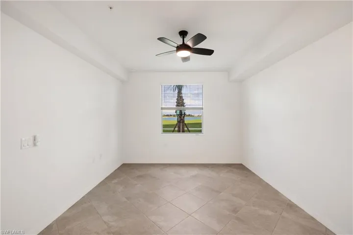 Empty room with ceiling fan and light tile flooring