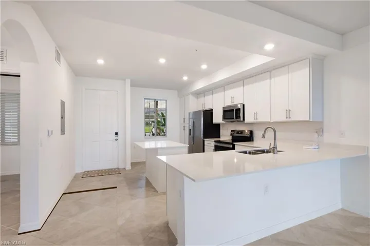 Kitchen with appliances with stainless steel finishes, white cabinetry, sink, and kitchen peninsula
