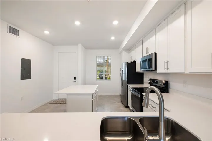 Kitchen featuring light tile floors, a kitchen island, white cabinetry, and appliances with stainless steel finishes