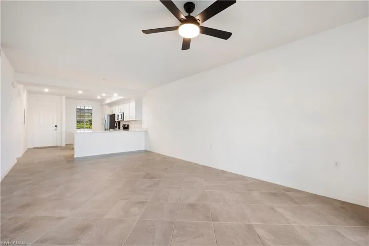 Unfurnished living room with ceiling fan and light tile floors
