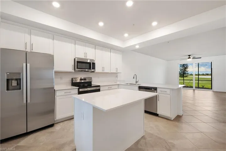 Kitchen featuring appliances with stainless steel finishes, ceiling fan, light tile floors, and a kitchen island