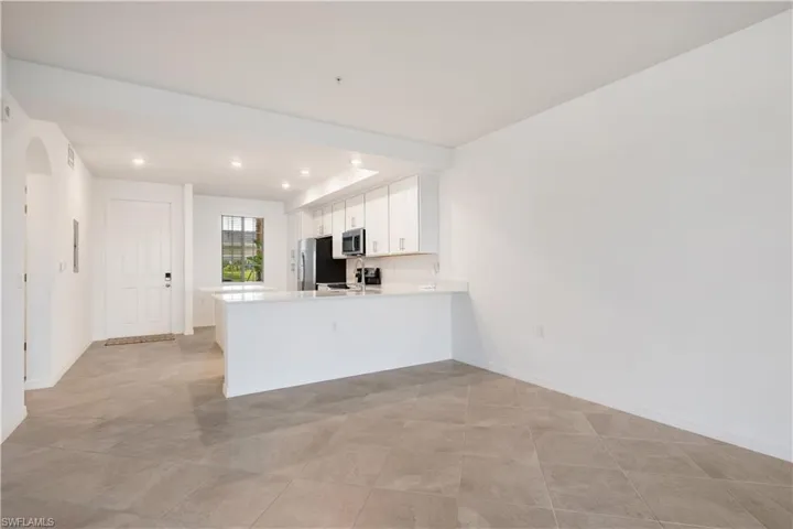 Kitchen with stainless steel appliances, white cabinetry, light tile flooring, and kitchen peninsula