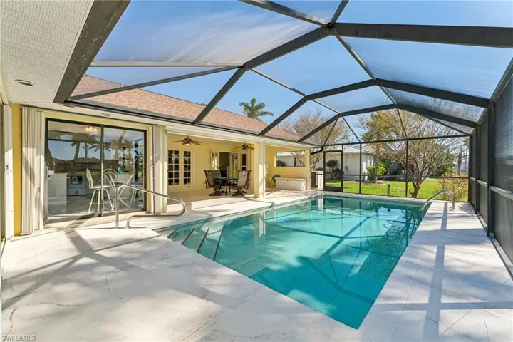 Outdoor pool with a ceiling fan, glass enclosure, and a patio