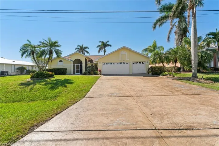 View of front of home with a garage, a front lawn, concrete driveway, and stucco siding
