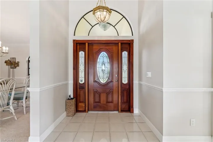 Foyer featuring a chandelier, light tile patterned floors, and baseboards