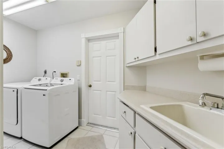 Laundry room with new washing machine and dryer, light tile patterned flooring, a sink, and cabinet space