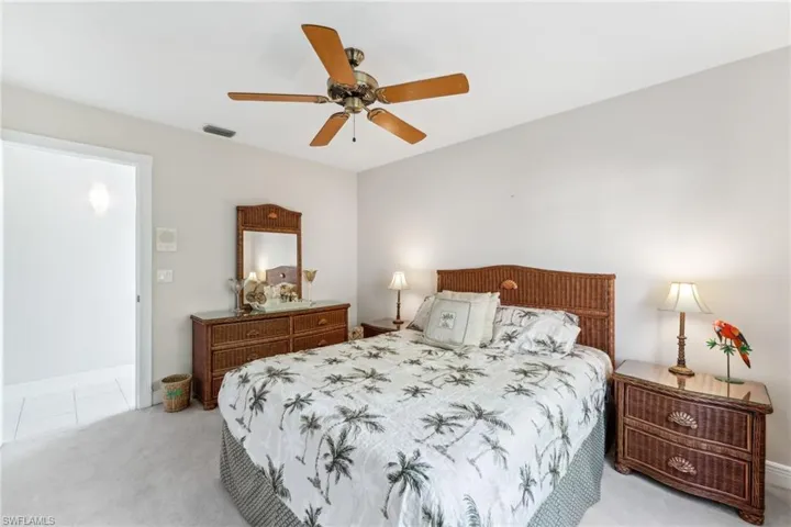 Bedroom with light carpet, visible vents, and a ceiling fan