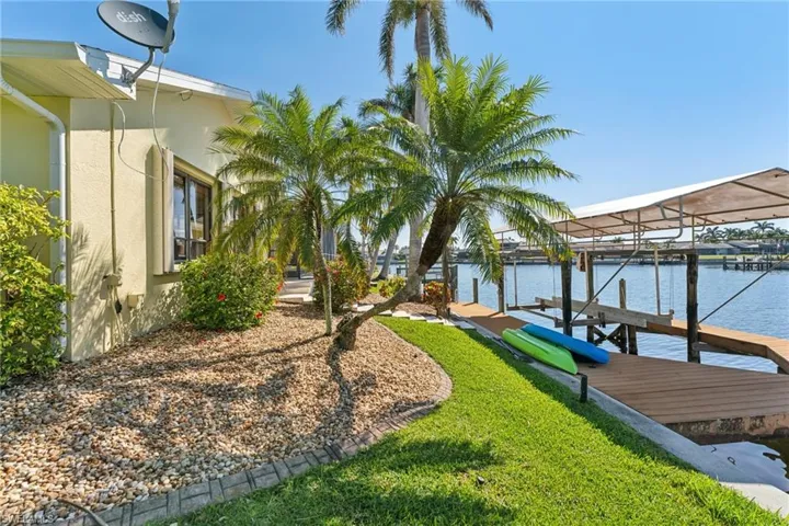 Dock area featuring a water view, a lawn, and boat lift