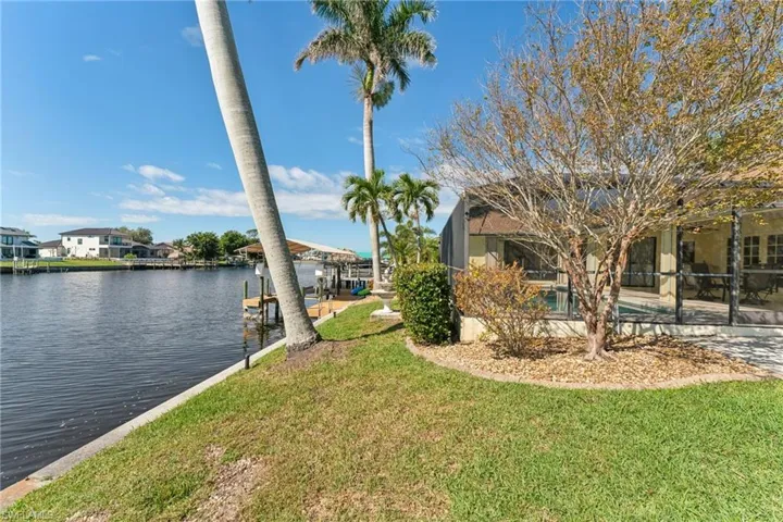 Dock area with glass enclosure, a water view, a lawn, a residential view, and an outdoor pool