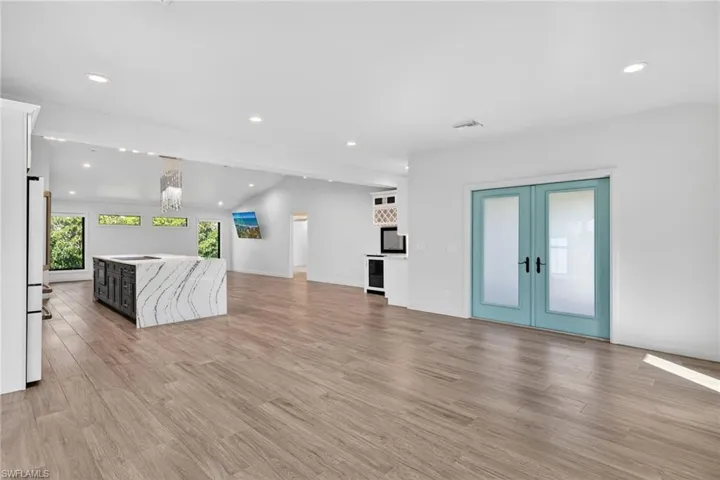 Featuring lofted ceiling, recessed lighting, french doors, and light wood floor.