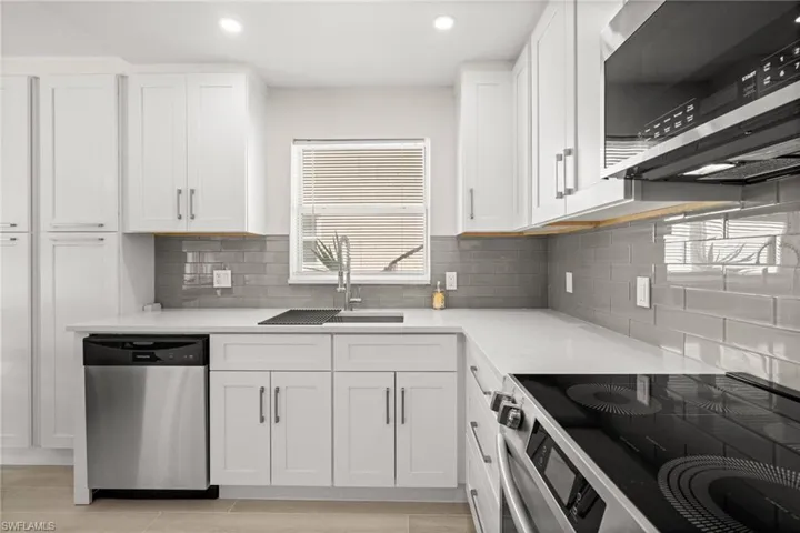 Kitchen with appliances with stainless steel finishes, white cabinetry, light stone counters, and recessed lighting