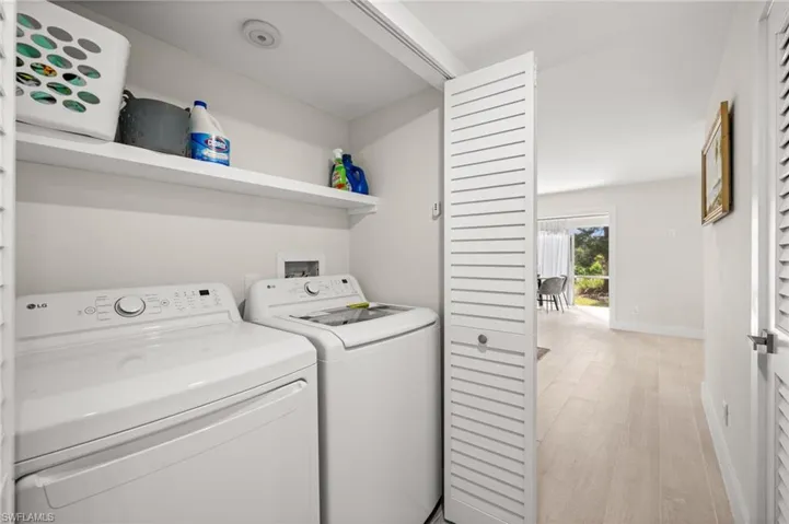 Laundry room with washing machine and clothes dryer and light wood finished floors