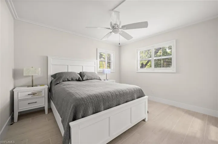 Bedroom with wood finish floors, ceiling fan, and crown molding