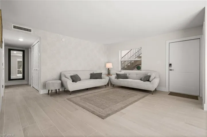 Living room featuring wood finish floors, wallpapered walls, stairs, and an accent wall