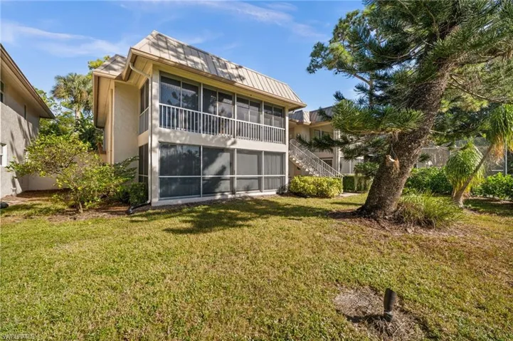 Back of property with a sunroom, stairway, a yard, and stucco siding