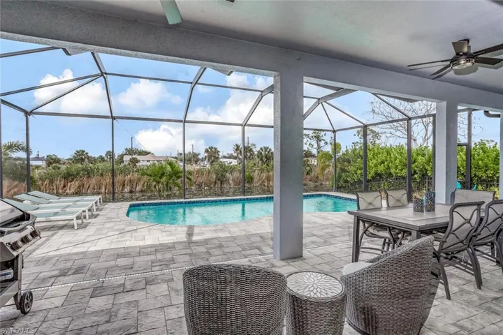 Outdoor pool with a patio area, a sunroom, a lanai, area for grilling, and outdoor dining space