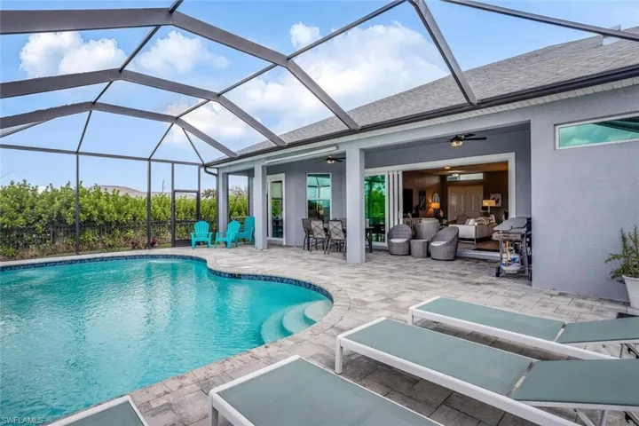 Swimming pool featuring a sunroom, a patio area, glass enclosure, and area for grilling