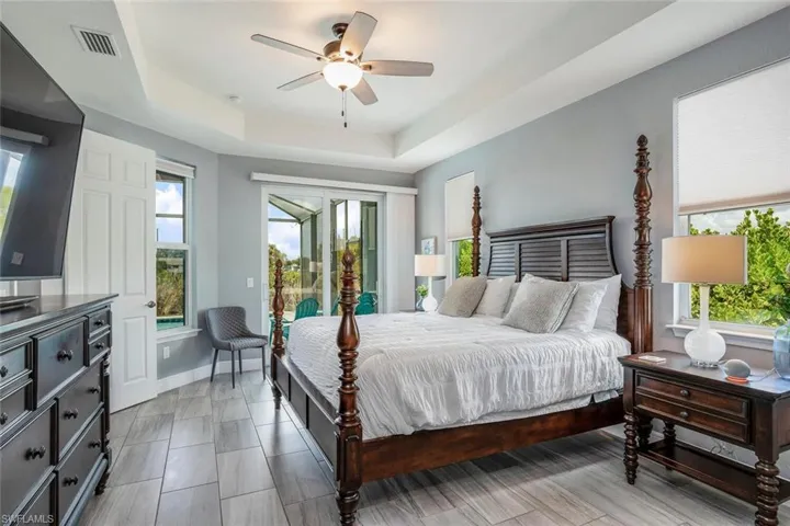 Bedroom featuring a tray ceiling, access to outside, and ceiling fan