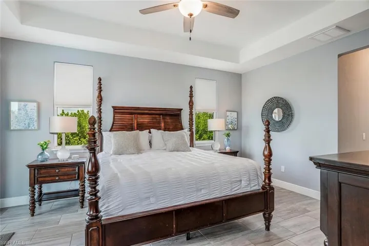 Bedroom with a raised ceiling, a ceiling fan, and wood tiled floors