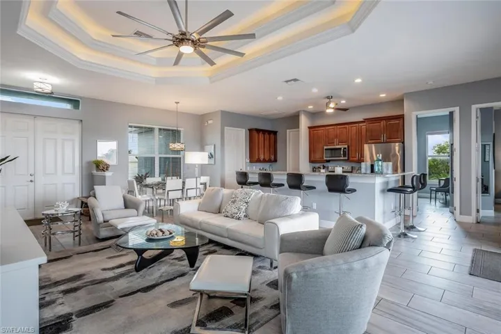 Living area with ceiling fan, ornamental molding, plenty of natural light, wood finish floors, and recessed lighting